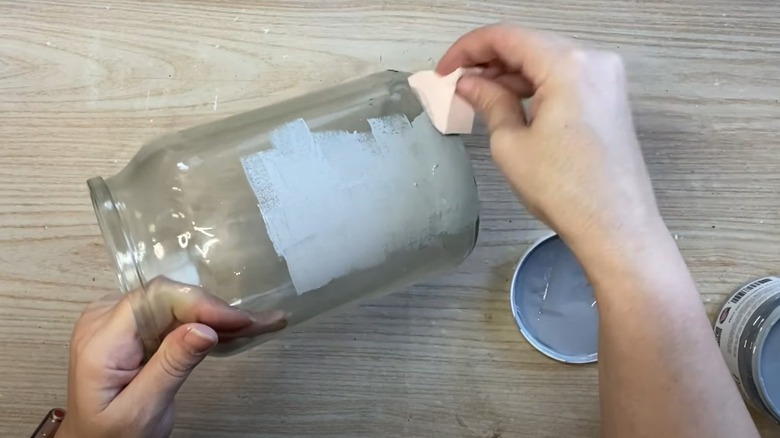 Person painting vase with sponge