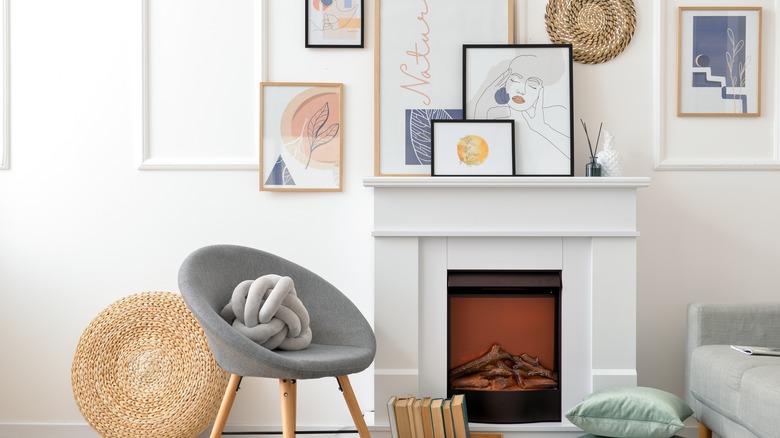 Chair next to mantelpiece with paintings of different sizes on it