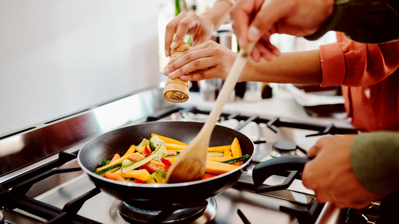 couple cooking with a nonstick pan and a bamboo spoon