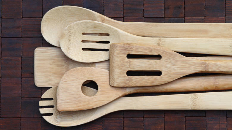 bamboo kitchen utensils placed over each other on wooden surface