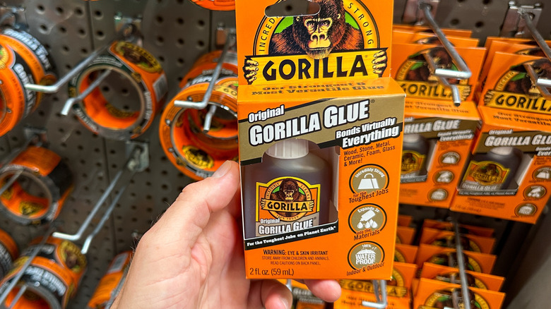 A hand holding a pack of Gorilla Glue at a store