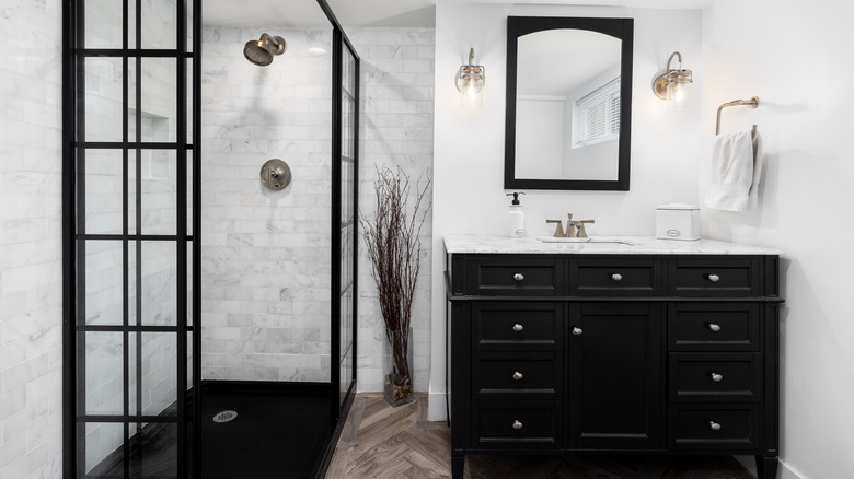 an all-white bathroom with black vanity, mirror, and shower enclosure