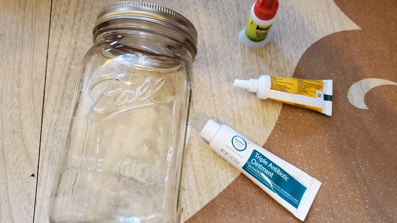 Mason Jar, bottle of Krazy Glue, and tubes of ointment on a table