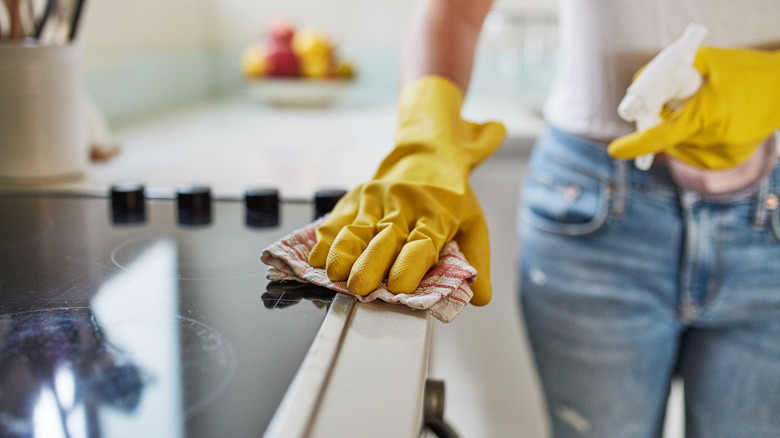 Person wiping stove top with cloth