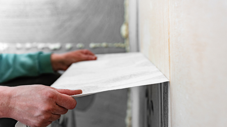 closeup of hands tearing off wallpaper from wall