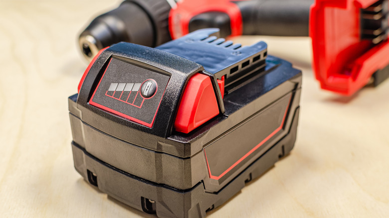 A battery charger with a cordless drill in the background