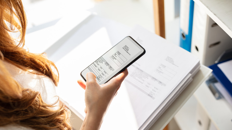 Woman photographing important papers with a smartphone