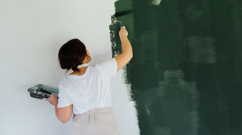 woman painting wall green