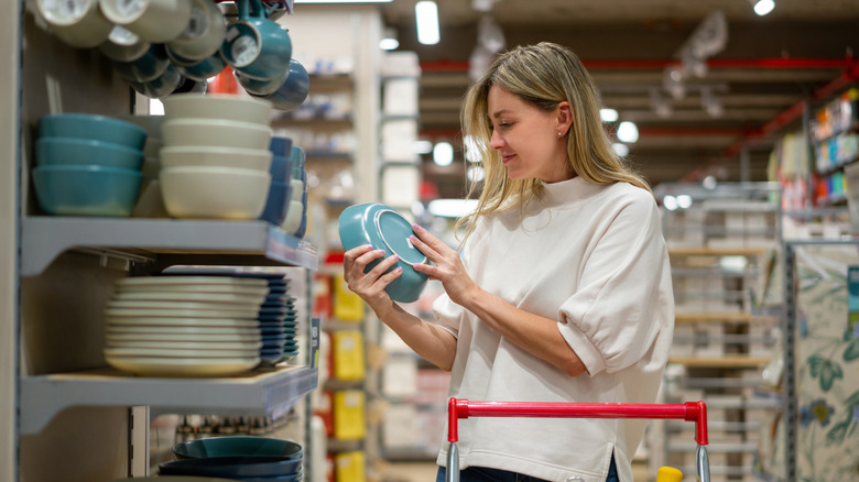 Woman shopping for dinnerware, set of plates, and bowls