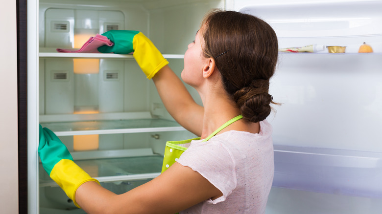 woman cleaning empty refrigerator