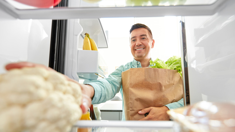 man putting groceries away