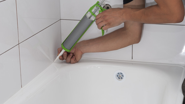 Caulk being applied around the edge of a bath