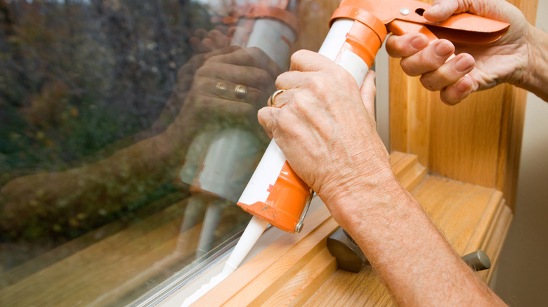 Caulking around a window frame indoors