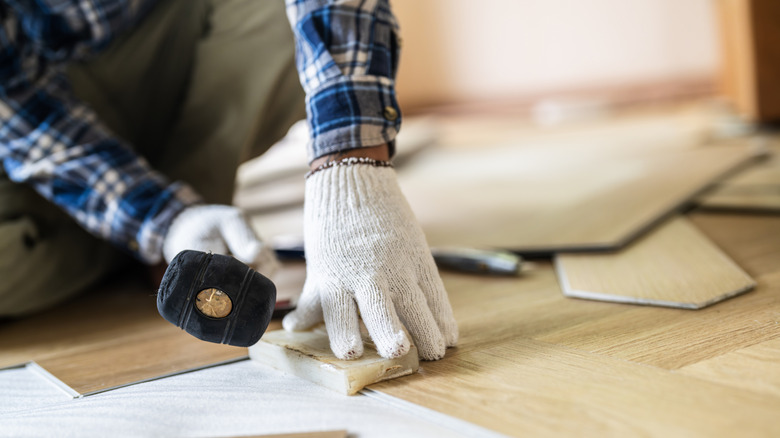 A person installing flooring panels with a mallet