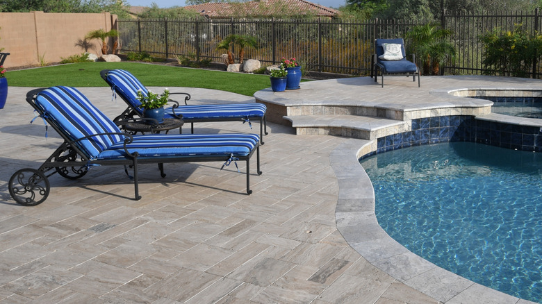 A travertine natural stone patio around a pool