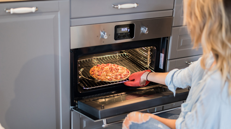 woman taking pizza out of oven