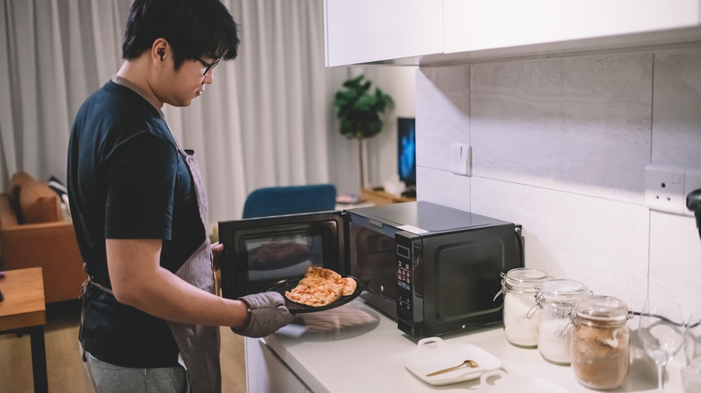 man heating pizza in microwave