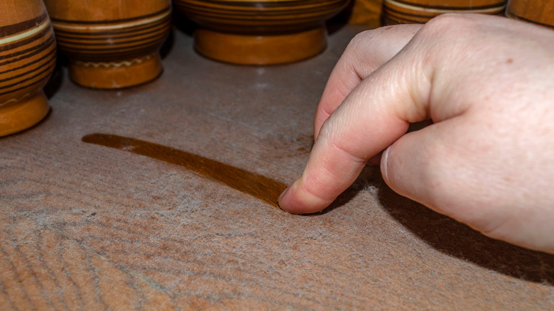 finger draws in dust on shelf