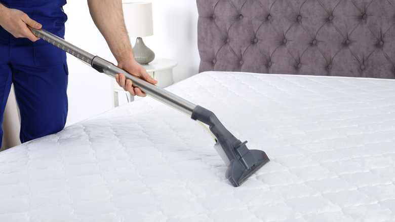man vacuuming a mattress