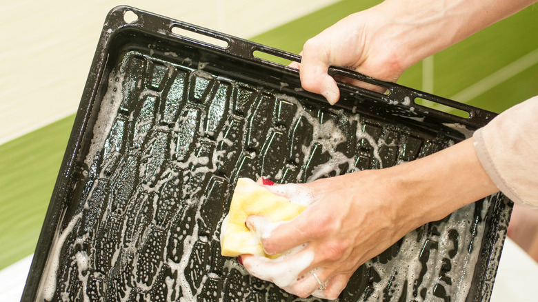 Hands washing baking pan 