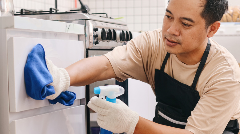 Man degreasing his kitchen cabinets with spray and cloth