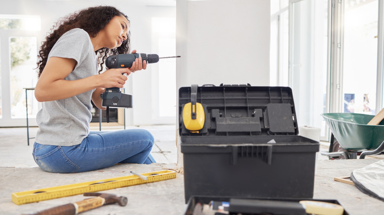 A woman using a drill in her home for a DIY project