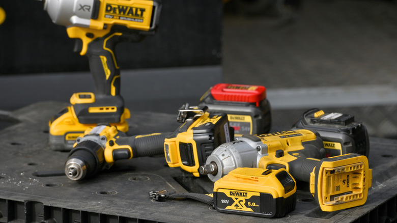 Multiple DeWalt power tools on top of a black surface