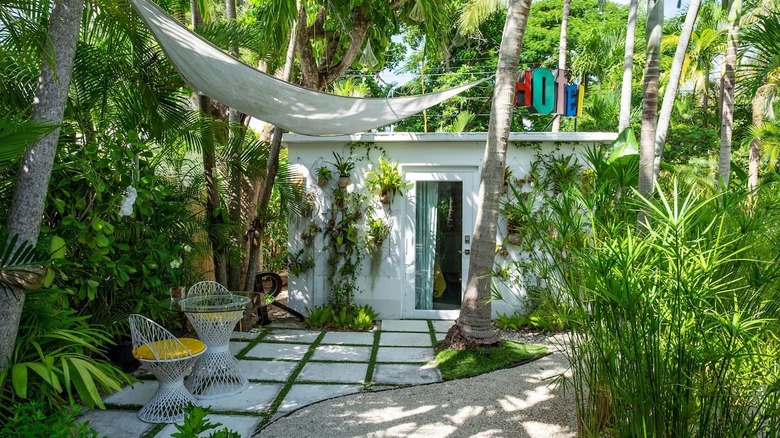 small white bungalow surrounded by greenery 