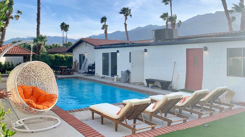 white chairs orange pillow next to pool