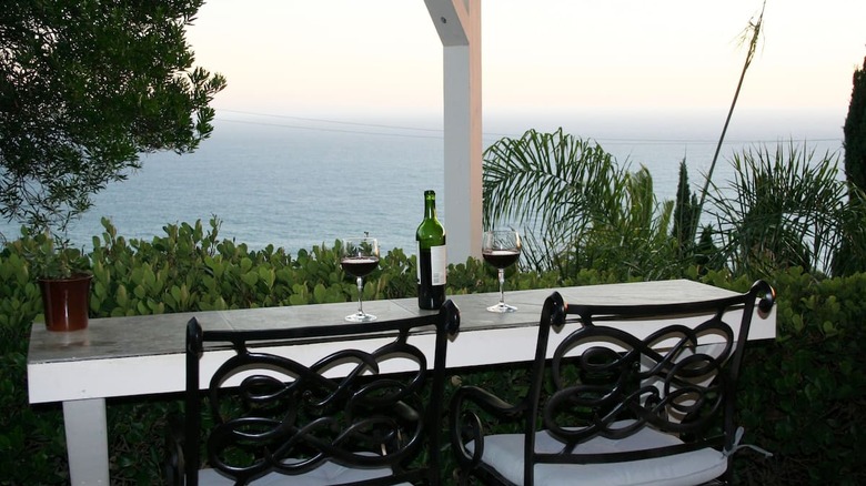 wine bottle and glasses overlooking ocean