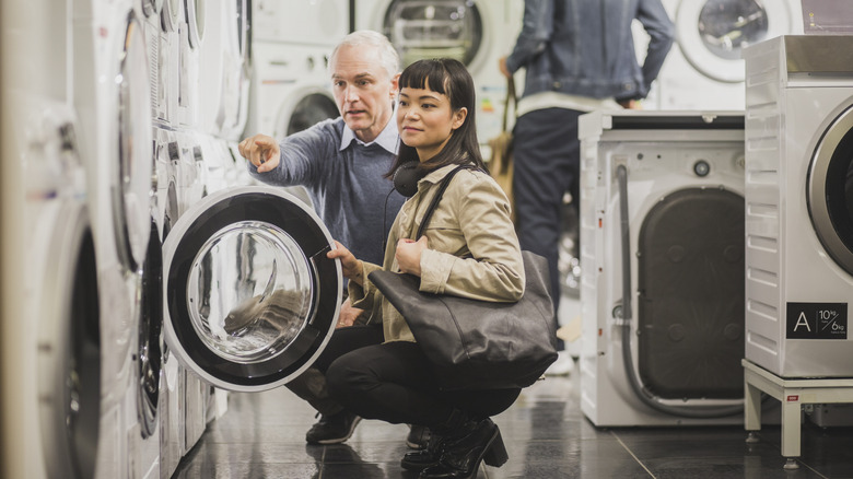 Senior gentleman pointing out a washing machine to a younger customer in appliance store