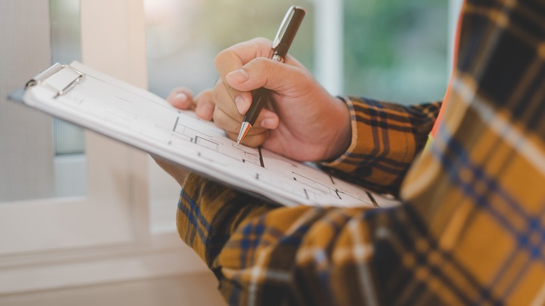 homeowner makes notes on clipboard