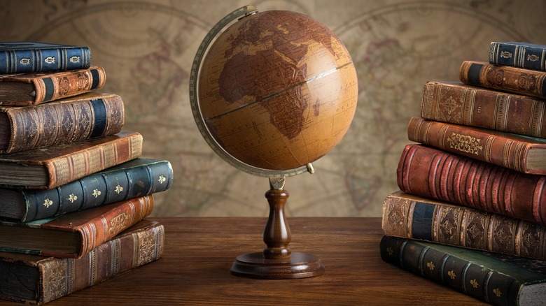 A globe on a desk between two stacks of books