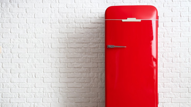 Red vintage fridge against a white brick wall