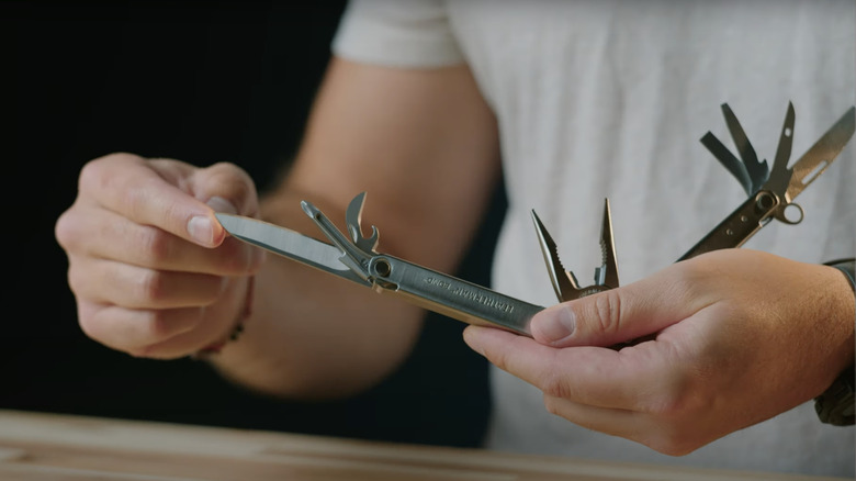 hands displaying stainless steel multitool attachments