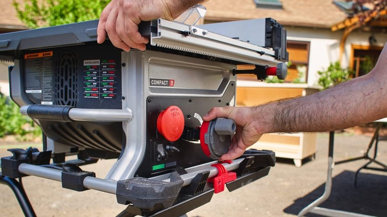 Man adjusting advanced table saw outside house