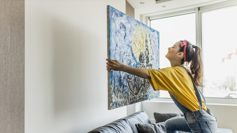 woman hanging art on wall