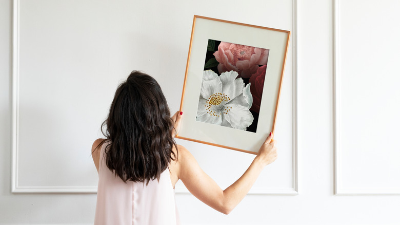 woman hanging framed art