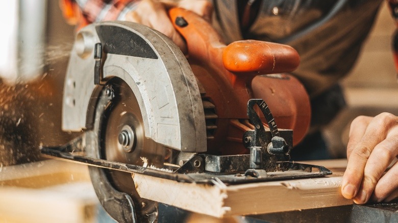 A person uses a circular saw to cut a door