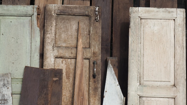 Salvaged doors stand upright against a wooden wall