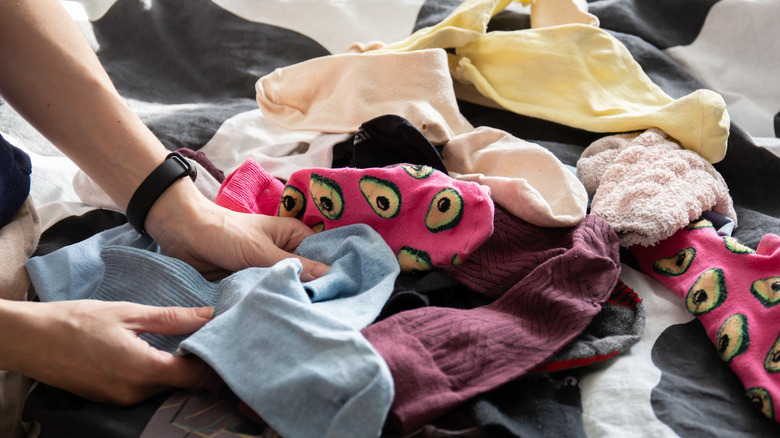 A woman's hand sorting out a mound of mismatched socks.