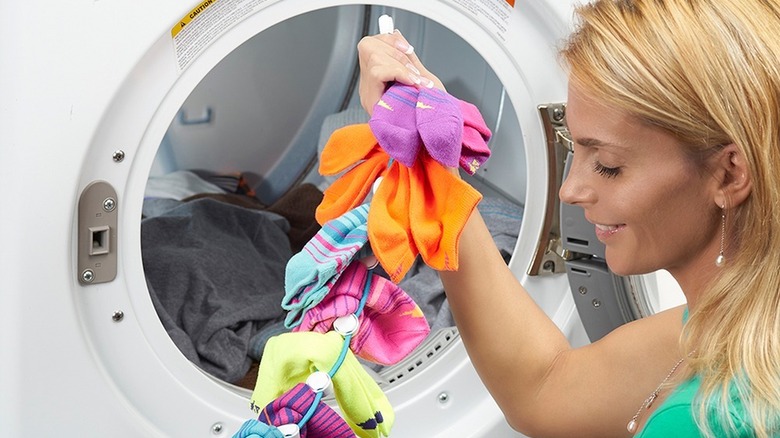 A woman next to a washing machine holding a SockDock.