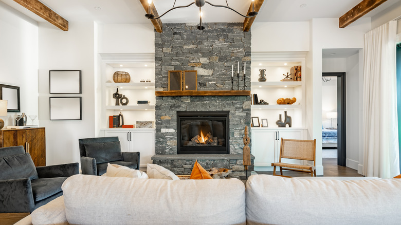 A modern living room with a stone fireplace and wood beam ceilings.