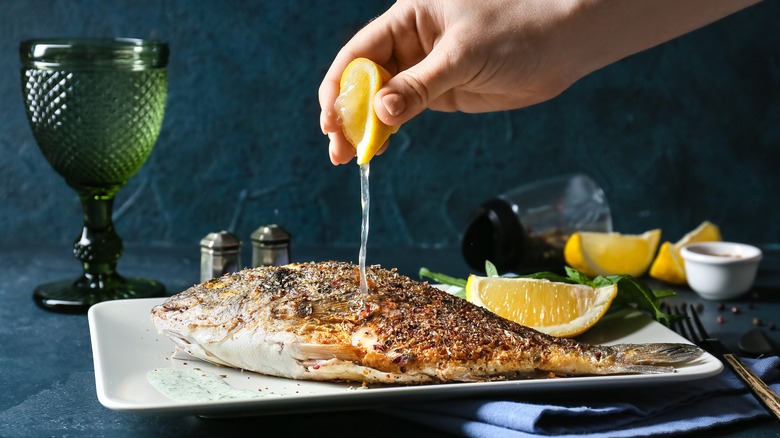 Woman squeezing lemon over fish 