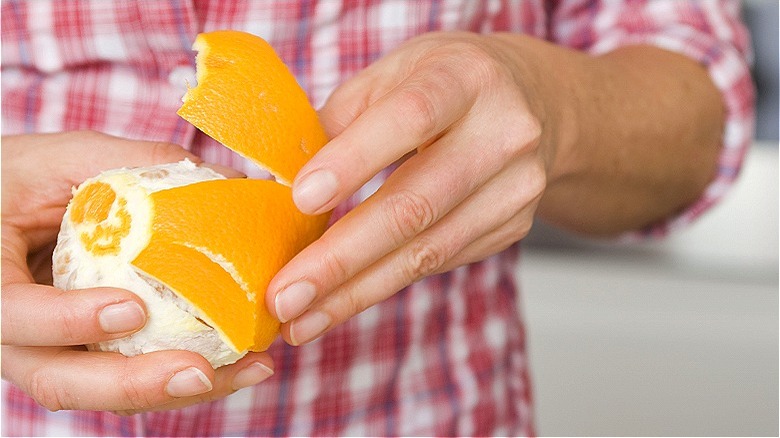 Person's hands peeling orange