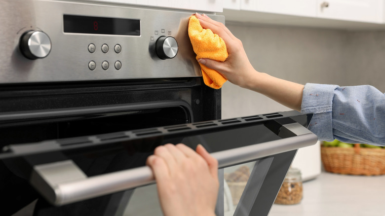 Woman cleaning outside of an oven door