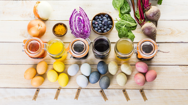 Colorful Easter eggs are lined up below jars of natural dye materials