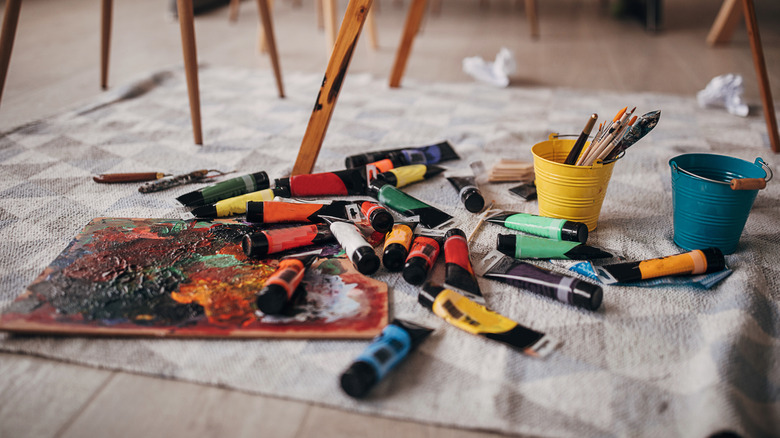 a mess of paint tubes and brushes on the floor