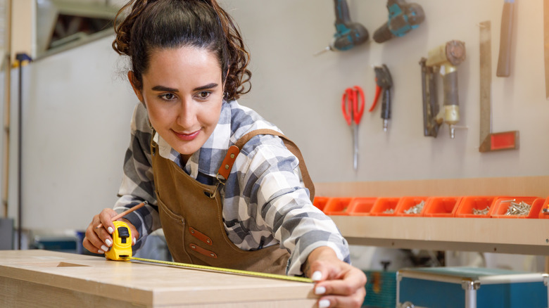 A person measuring a wood shelf