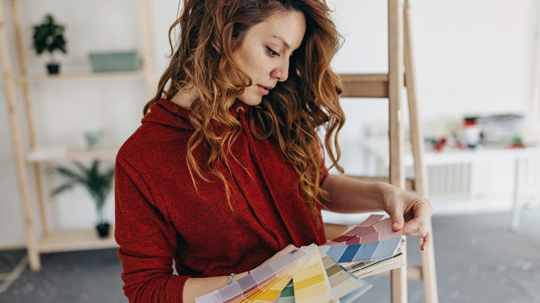 A woman in a red sweater sifting through paint palettes.